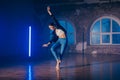 Young woman in casual style - jeans and leather jacket doing ballet in modern studio. Attractive ballerina practices in Royalty Free Stock Photo