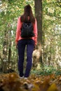 Young woman in casual wear walking in the autumn forest, view from the bottom. Rear view of female brunette standing in fall Royalty Free Stock Photo