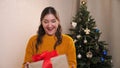 Young woman catches an unexpectedly tossed box with a gift on the background of a christmas tree