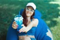 A young woman of Caucasian appearance in summer sitting on a puff on a lawn and having fun, makes emotions