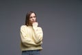 Young upset woman in yellow sweater on gray background holding hands in fists Royalty Free Stock Photo