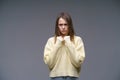 Young upset woman in yellow sweater on gray background holding hands in fists Royalty Free Stock Photo