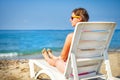 Young woman in chaise lounge at the sea beach. Girl relax on beach.