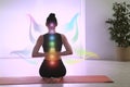 Young woman with chakra points practicing yoga in studio. Healing energy
