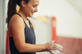 Young woman with chalked hands posing at indoor climbing gym wall