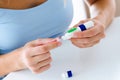 Young woman changing pencil needle to get tested for glucose on white background.