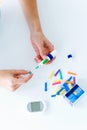 Young woman changing pencil needle to get tested for glucose on white background.