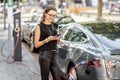 Woman charging electric car outdoors Royalty Free Stock Photo