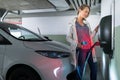 Young woman charging an electric vehicle in an underground garage