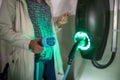 Young woman charging an electric vehicle in an underground garage