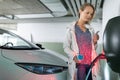 Young woman charging an electric vehicle