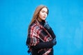 Young woman with a checkered red scarf near a blue wall