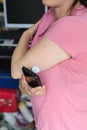 Young woman checking her glucose level before work, by using the mobile and the glucose sensor placed on her arm. Health and Royalty Free Stock Photo