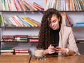 young woman checking her mobile phone while sitting with a hot drink Royalty Free Stock Photo