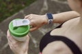 A young woman checking her progress on a smartwatch. Fitness sporty girl holding a bottle of water Royalty Free Stock Photo