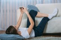 Young woman checking her smart phone lying on carpet Royalty Free Stock Photo