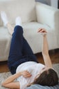 Young woman checking her smart phone lying on carpet Royalty Free Stock Photo