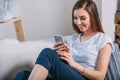 Young woman checking her smart phone sitting on sofa Royalty Free Stock Photo