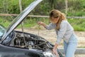 Young woman checking the oil level in the engine under the hood of a black car with a dipstick Royalty Free Stock Photo