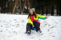 The young woman cheerfully moves down from a hill on the saucer sled.