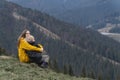 Young woman and child boy sit on hillside. Mother and son rest and sit in an embrace on mountains background