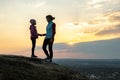 Young woman and child girl, mom and daughter standing on grassy mountain hill holding hands at sunset. Family tourism