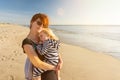 Young woman with child in her arms relaxes on the beach and enjoys the sunset