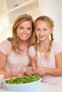 Young woman with child splitting pea in kitchen