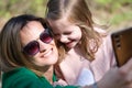 Young woman with child taking selfie on mobile phone in park Royalty Free Stock Photo