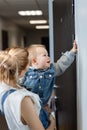 Young woman with a child visiting friends, end of quarantine, kid presses the doorbell Royalty Free Stock Photo