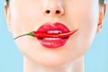 Young woman with chili red pepper isolated en blue background. Sexy female lips. Hot seductive girl Royalty Free Stock Photo