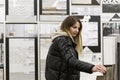 A young woman chooses ceramic tiles in a hardware store. Beautiful blonde in a black jacket. Construction, design and repair Royalty Free Stock Photo