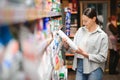 A young woman chooses household chemicals in a supermarket. Means for washing and cleaning the house Royalty Free Stock Photo