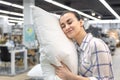 A young woman chooses a pillow in a home improvement store. Royalty Free Stock Photo