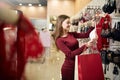 Young woman chooses brassiere among set in a boutique. Pretty girl considers bra with shopping bags in her hand in Royalty Free Stock Photo