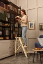 Young woman choosing book in home library Royalty Free Stock Photo