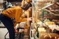 Young woman choosing cakes in grocery store