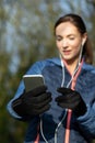 Young Woman Choosing Music To Listen To On Mobile Phone Before Exercising In Park Royalty Free Stock Photo