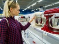 Woman choosing new kitchen mixer in household appliances store