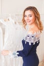 Young woman choosing transparent light lace dress among clothes on a rack. Shopping in private small designer`s shop Royalty Free Stock Photo