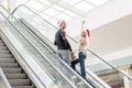 young woman in christmas hat with raised arms looking at camera while her boyfriend Royalty Free Stock Photo