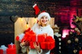 Young woman with christmas present boxes in front of christmas tree. Cheerful young woman wearing christmas costume over Royalty Free Stock Photo