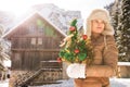 Young woman with Christmas tree standing near mountain house Royalty Free Stock Photo