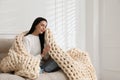 Young woman with chunky knit blanket on sofa at home Royalty Free Stock Photo