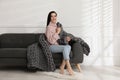 Young woman with chunky knit blanket on sofa at home Royalty Free Stock Photo