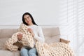 Young woman with chunky knit blanket on sofa at home Royalty Free Stock Photo