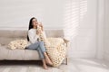Young woman with chunky knit blanket on sofa at home Royalty Free Stock Photo