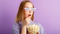 Young woman in cinema glasses watching 3d movie in cinema. Smiling teenager girl movie viewer in glasses eating popcorn Royalty Free Stock Photo