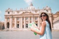 Happy young woman with city map in Vatican city and St. Peter`s Basilica church, Rome, Italy. Royalty Free Stock Photo