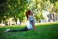 Young woman in city park on green grass doing stretching fitness exercises outdoors Royalty Free Stock Photo